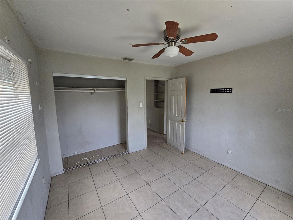 A bedroom features light-colored tile flooring, a ceiling fan, a closet, and an open doorway — 1511 27TH STREET S, ST PETERSBURG, FL