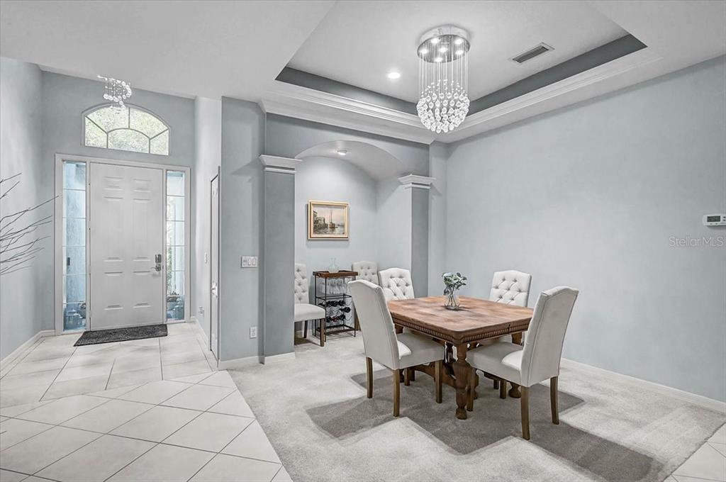 A dining room features a tray ceiling, crystal chandelier, and a square wooden table — 103 BISHOPS COURT ROAD, OSPREY, FL