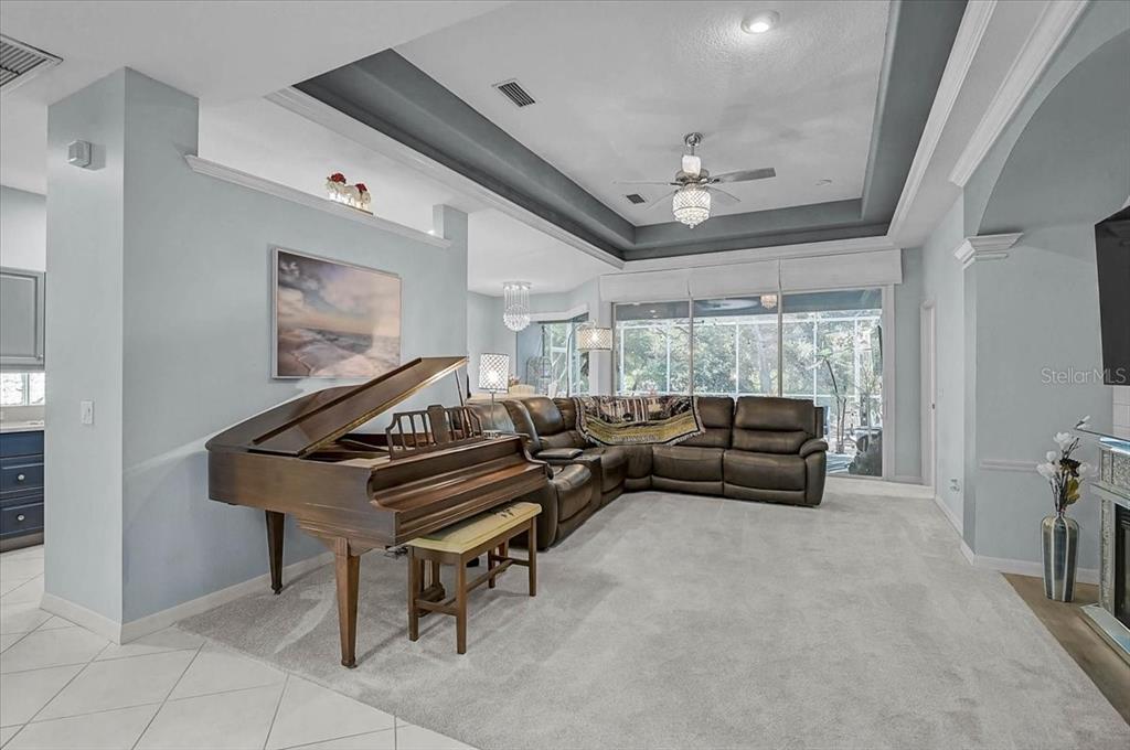 A living room features a grand piano, a large sectional sofa, and a tray ceiling — 103 BISHOPS COURT ROAD, OSPREY, FL