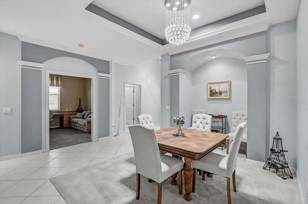 A dining room features a wooden table, white chairs, a crystal chandelier, and arched alcoves — 103 BISHOPS COURT ROAD, OSPREY, FL
