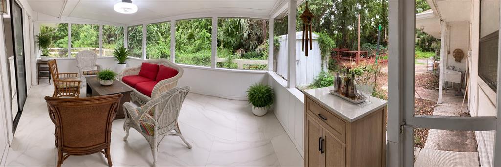 A panoramic view of a screened-in porch with white tile flooring and wicker furniture — 1735 TIMOCUAN WAY UNIT A, LONGWOOD, FL