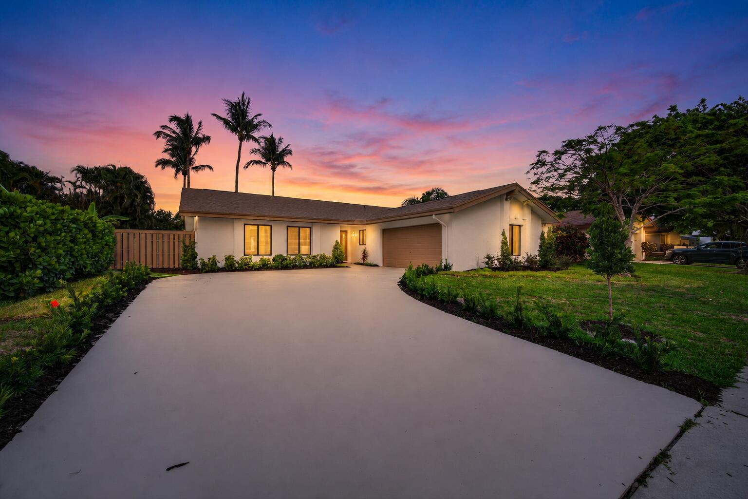 A single-story house with a concrete driveway and palm trees under a colorful sunset sky — 3088 NW 26th Avenue, Boca Raton FL 33434, BOCA RATON, FL