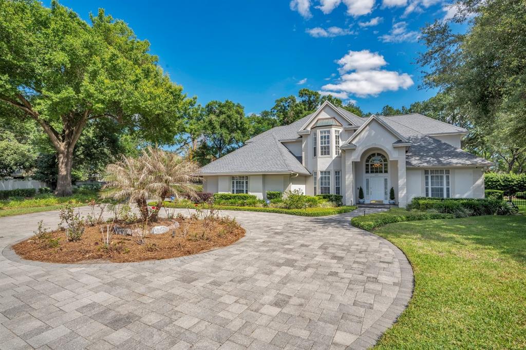 A large two-story house with a gray roof and a circular paver driveway — 1451 HOLLINGSWORTH OAKS DRIVE, LAKELAND, FL