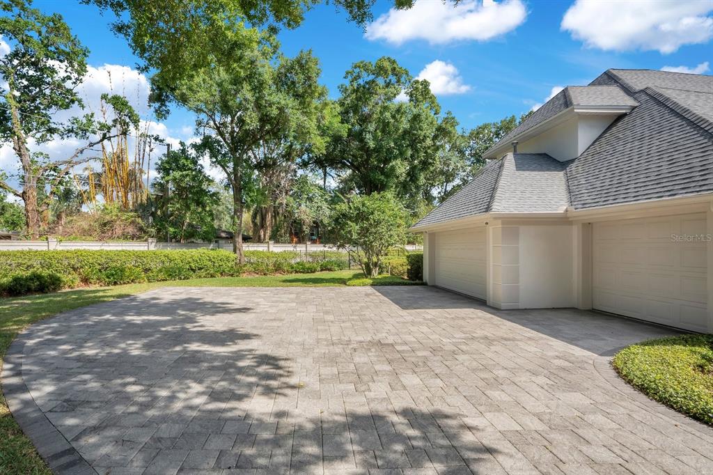 A paved driveway leads to a multi-car garage beside a house with a gray roof — 1451 HOLLINGSWORTH OAKS DRIVE, LAKELAND, FL