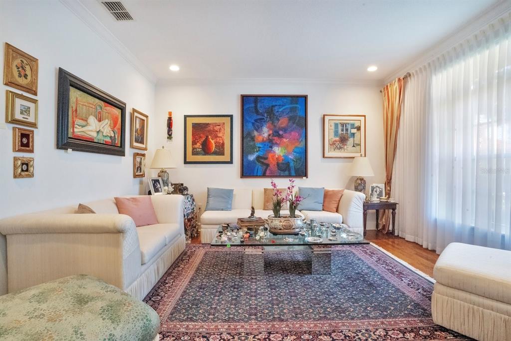 A living room features a white sofa, a glass coffee table, and several framed paintings — 1451 HOLLINGSWORTH OAKS DRIVE, LAKELAND, FL
