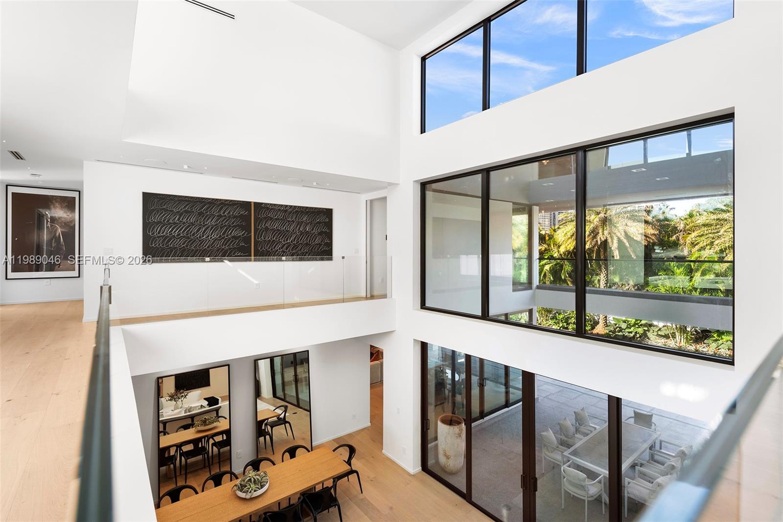 A two-story interior space features white walls, hardwood floors, large windows, and a dining area — 128 Ocean Blvd, Golden Beach FL 33160, GOLDEN BEACH, FL