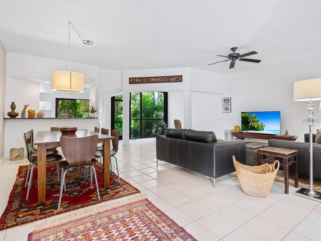 A dining area and living room with white tile floors, a rug, and large windows — 1678 STARLING DRIVE UNIT 102, SARASOTA, FL