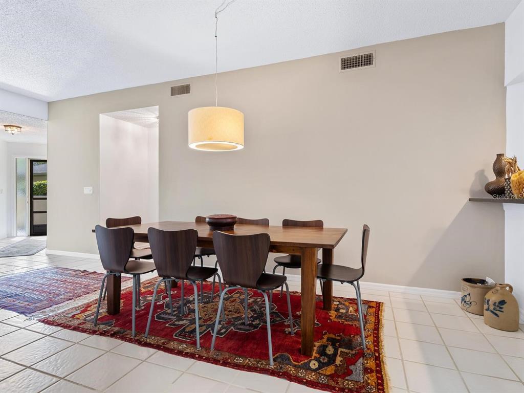 A dining room features a wooden table, six chairs, and a large patterned area rug — 1678 STARLING DRIVE UNIT 102, SARASOTA, FL