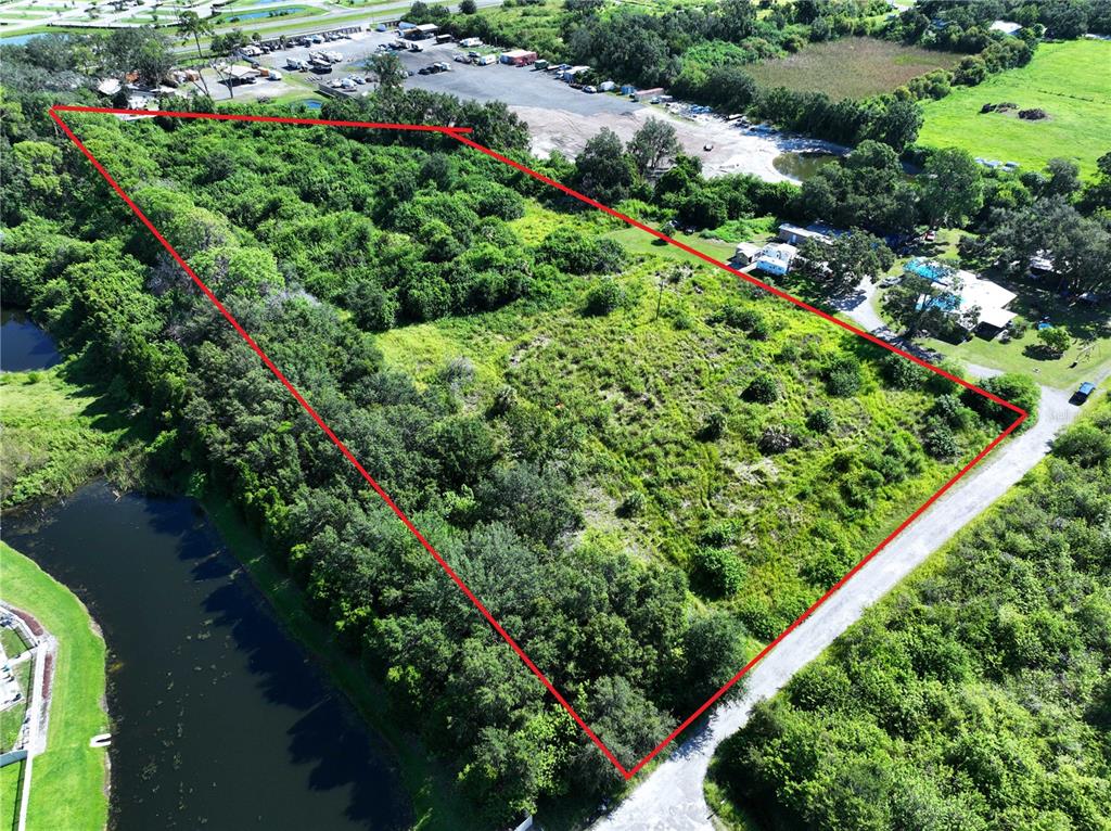 An aerial view shows a triangular plot of land outlined in red near a pond — 10TH AVE SE, RUSKIN, FL