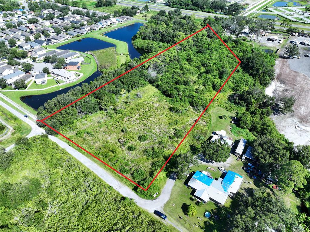An aerial view shows a rectangular, undeveloped plot of land outlined in red — 10TH AVE SE, RUSKIN, FL
