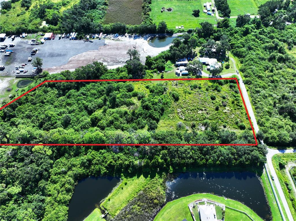 An aerial view shows a rectangular plot of land outlined in red near a road — 10TH AVE SE, RUSKIN, FL