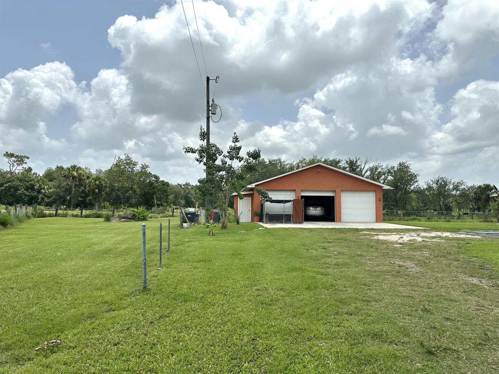 A detached orange garage with three bays sits on a large, grassy lot — 840 NW 141st Street, Okeechobee FL 34972, OKEECHOBEE, FL