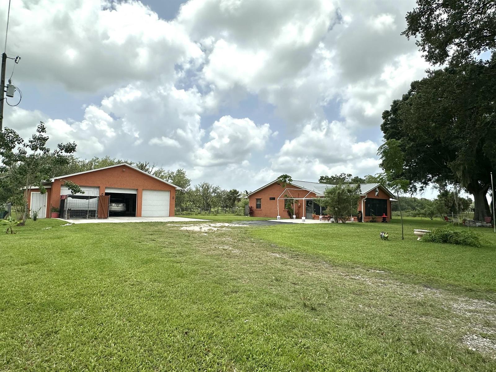 An orange house and a matching detached garage sit on a large, grassy lot — 840 NW 141st Street, Okeechobee FL 34972, OKEECHOBEE, FL