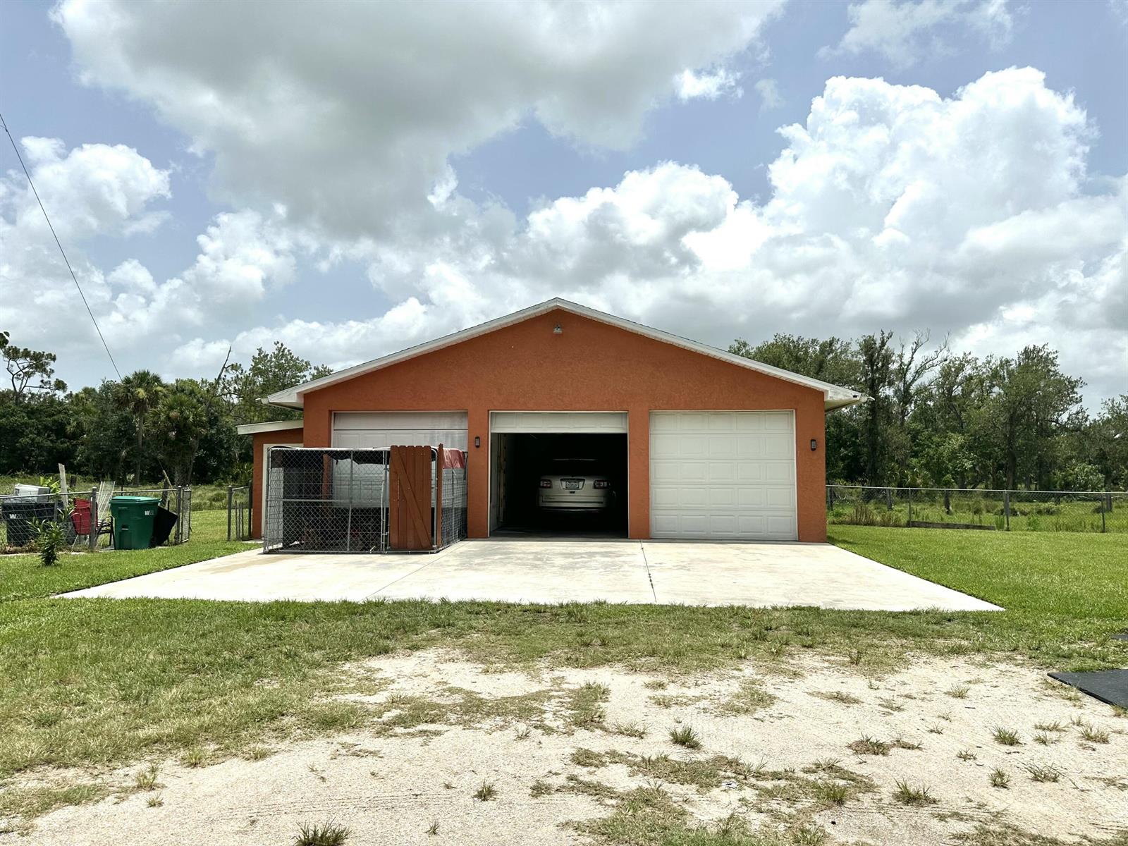 A detached three-car garage with an orange stucco exterior and a concrete driveway — 840 NW 141st Street, Okeechobee FL 34972, OKEECHOBEE, FL