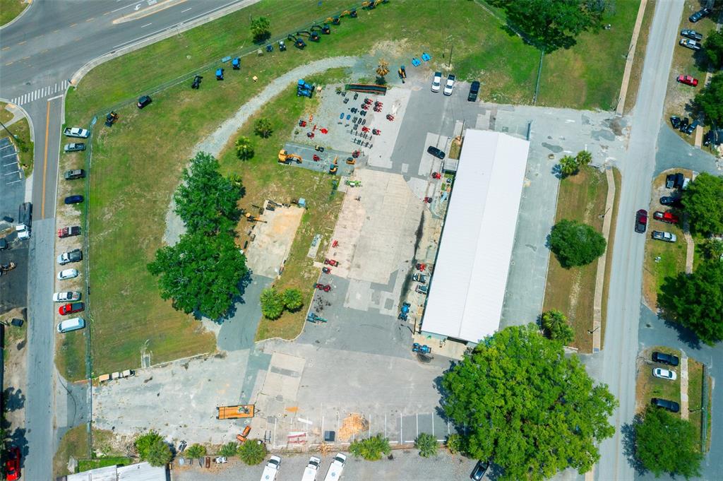 An aerial view shows a commercial property with a large warehouse, parking lot, and equipment — 1904 NE JACKSONVILLE ROAD, OCALA, FL