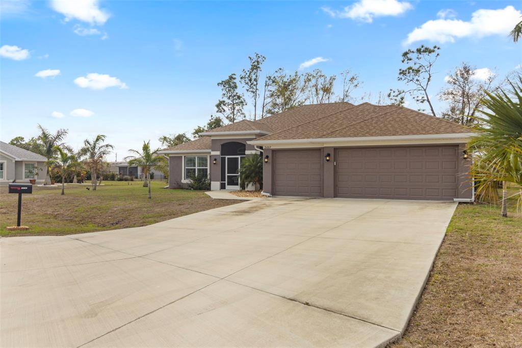 A single-story house with a brown roof, gray exterior, and a two-car garage — 26069 PARANA DRIVE, PUNTA GORDA, FL