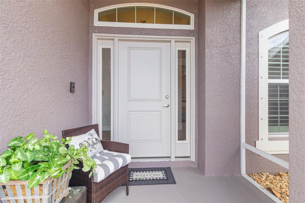 A front entryway features a white door with sidelights, a transom window, and a chair — 26069 PARANA DRIVE, PUNTA GORDA, FL