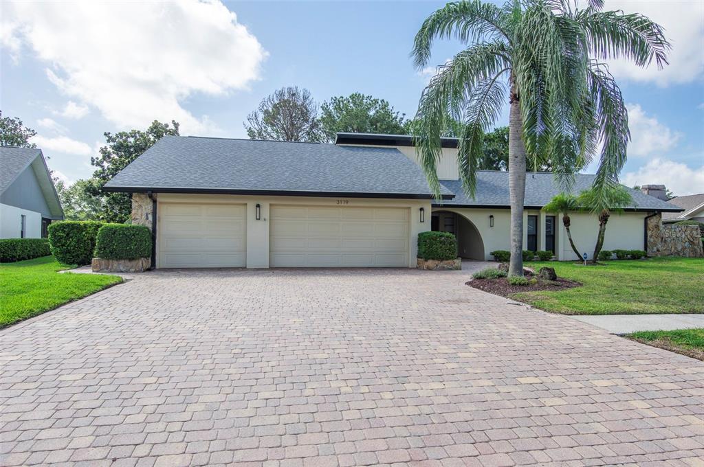 A single-story house with a three-car garage, a paved driveway, and a large palm tree — 3119 HYDE PARK DRIVE, CLEARWATER, FL
