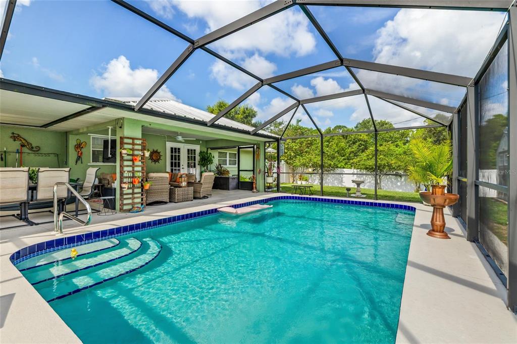 A swimming pool with steps sits inside a screened-in lanai next to a patio area — 2776 JACOBS STREET, PORT CHARLOTTE, FL