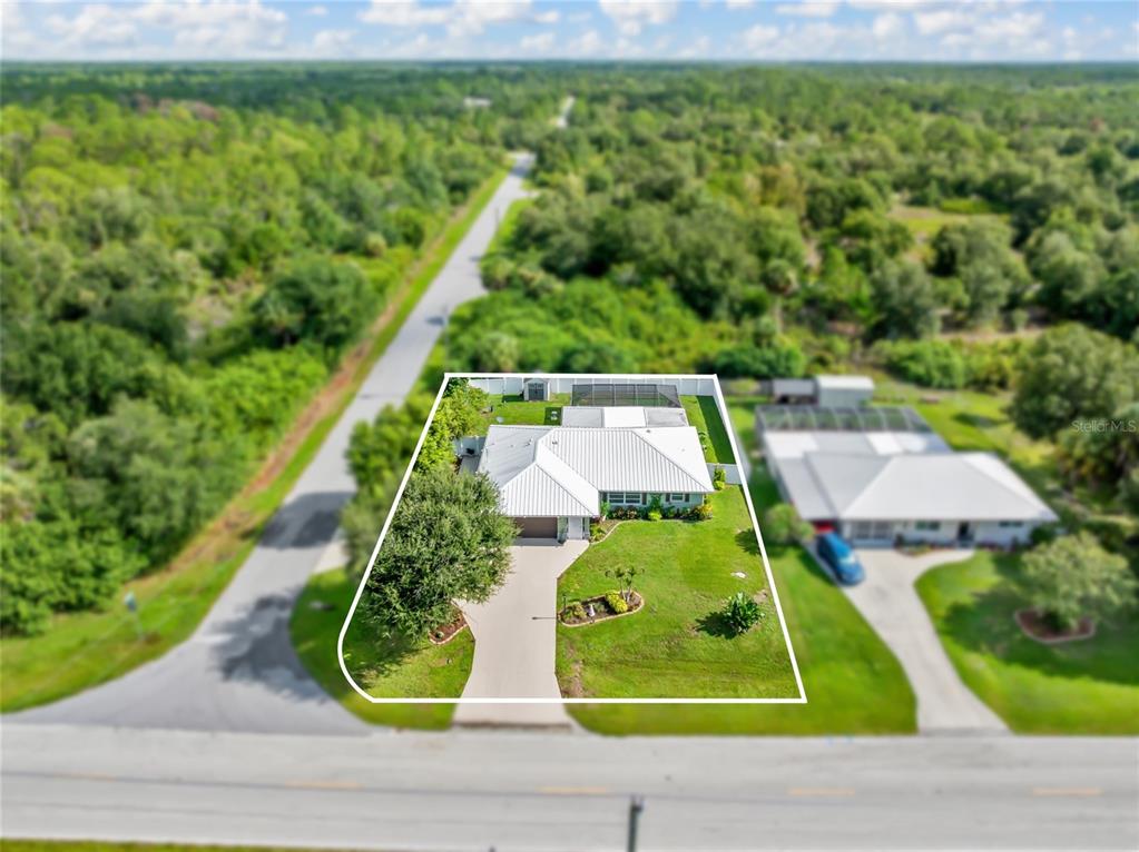 An aerial view shows a single-story house with a metal roof and a fenced backyard — 2776 JACOBS STREET, PORT CHARLOTTE, FL