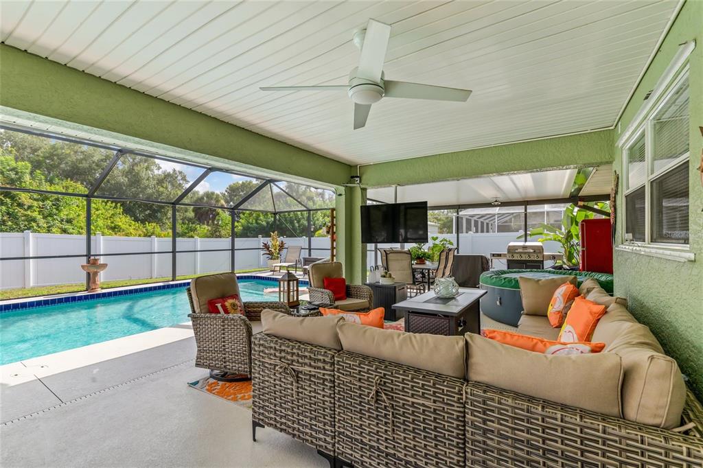 A covered patio features a swimming pool, outdoor seating, a television, and a hot tub — 2776 JACOBS STREET, PORT CHARLOTTE, FL