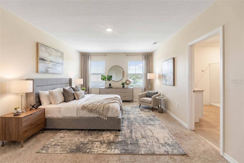 A bedroom features a gray upholstered bed, a wooden nightstand, and a dresser with a mirror — 17448 HARVEST MOON WAY, BRADENTON, FL