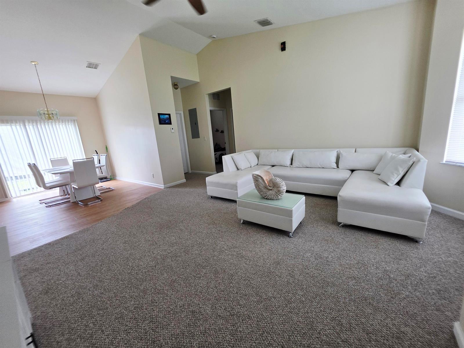 A living room with beige carpet, a large white sectional sofa, and an adjacent dining area — 17331 38th Road N, FL 33470, FL