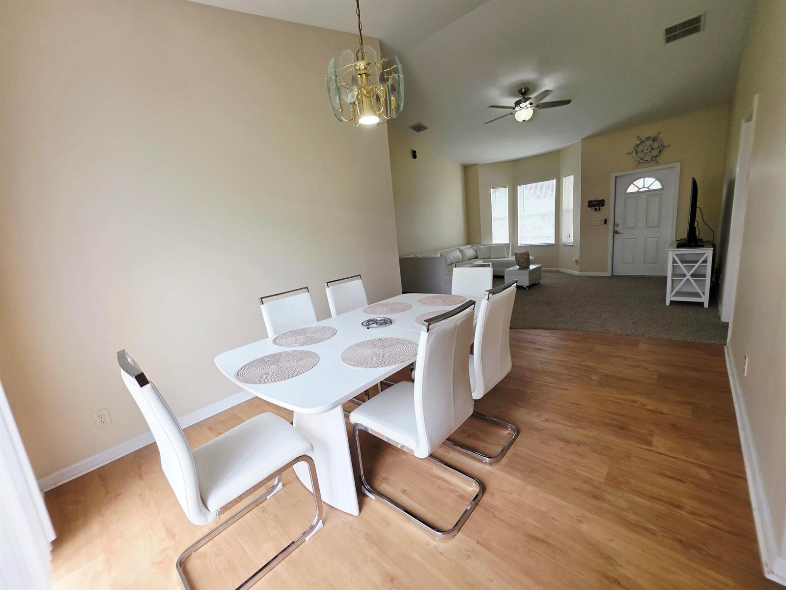 A dining area with a white table and chairs sits adjacent to a carpeted living room — 17331 38th Road N, FL 33470, FL