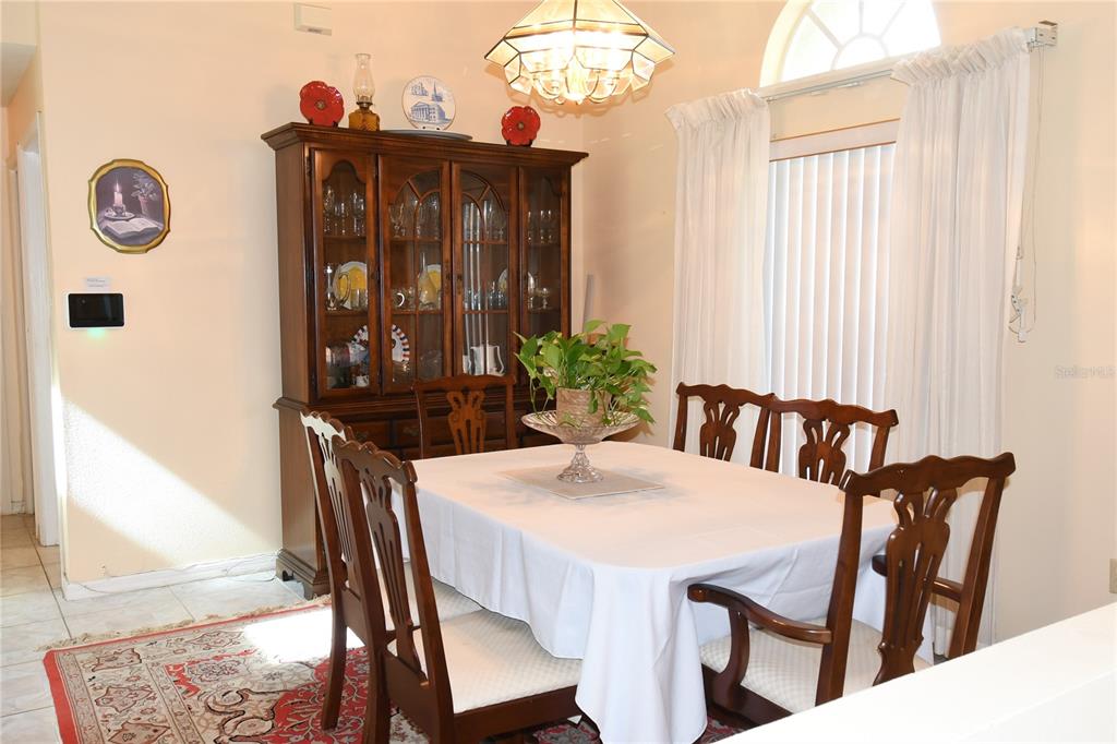 A dining room features a wooden hutch, a table with a white cloth, and chairs — 10027 SW 64TH COURT, OCALA, FL