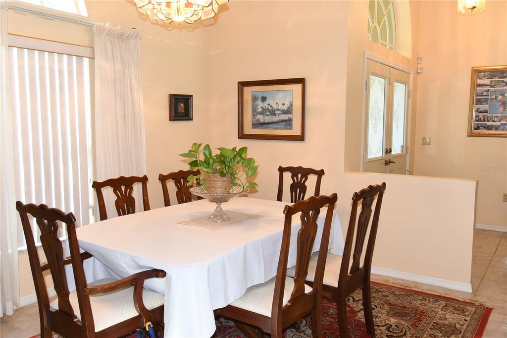A dining room features a white-clothed table, six wooden chairs, and a patterned area rug — 10027 SW 64TH COURT, OCALA, FL