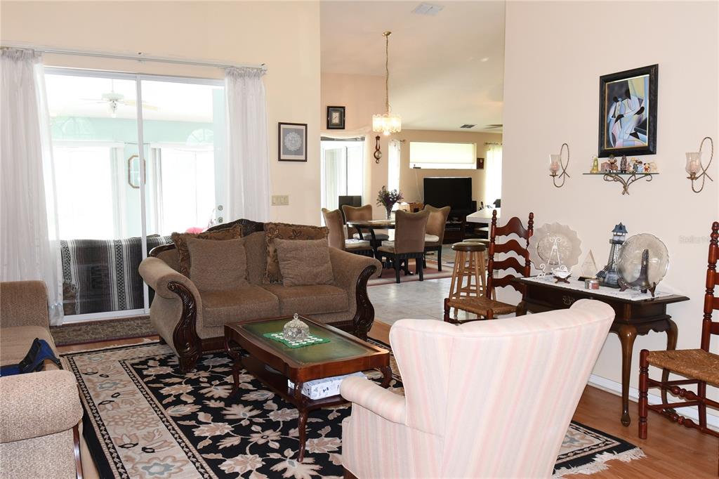 A living room with a brown sofa, patterned rug, and an open view to the dining area — 10027 SW 64TH COURT, OCALA, FL
