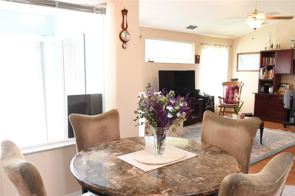 A dining area with a round marble table sits in front of a living room — 10027 SW 64TH COURT, OCALA, FL