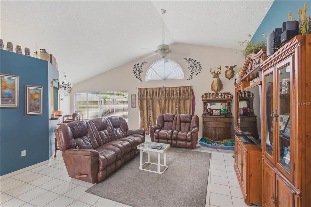 A living room features vaulted ceilings, tile floors, brown leather furniture, and a large entertainment center — 108 N BRISTOL CIRCLE, SANFORD, FL