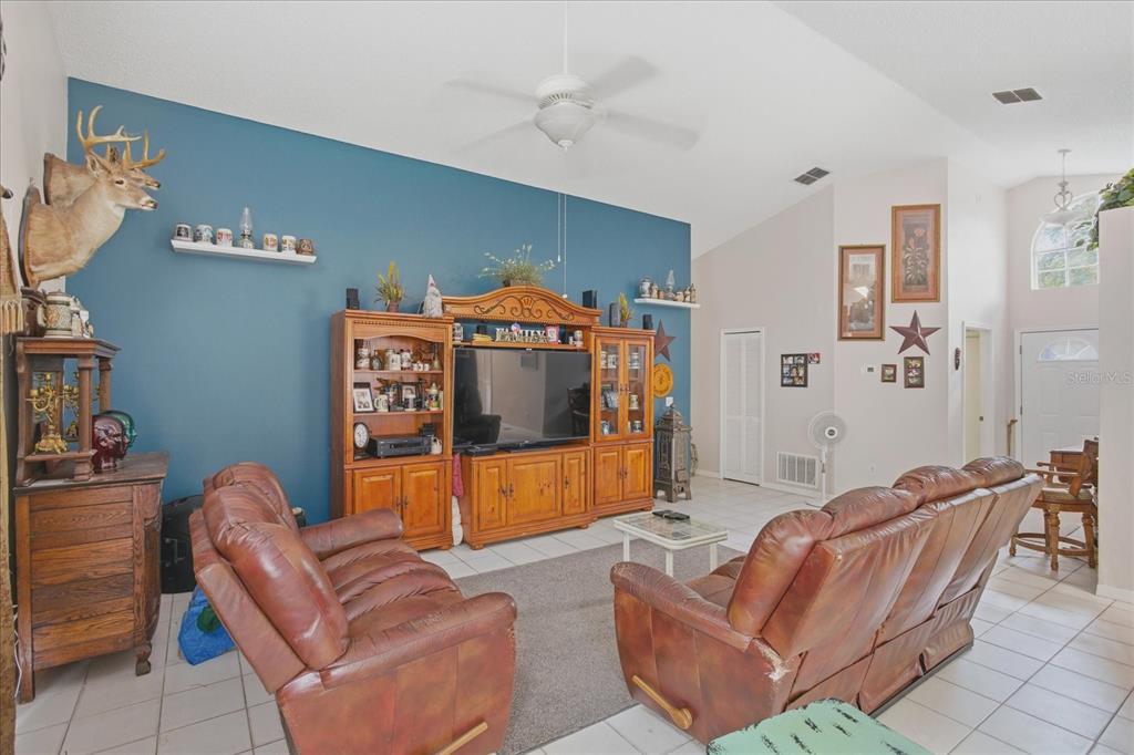 A living room features a blue accent wall, wooden entertainment center, and two leather sofas — 108 N BRISTOL CIRCLE, SANFORD, FL