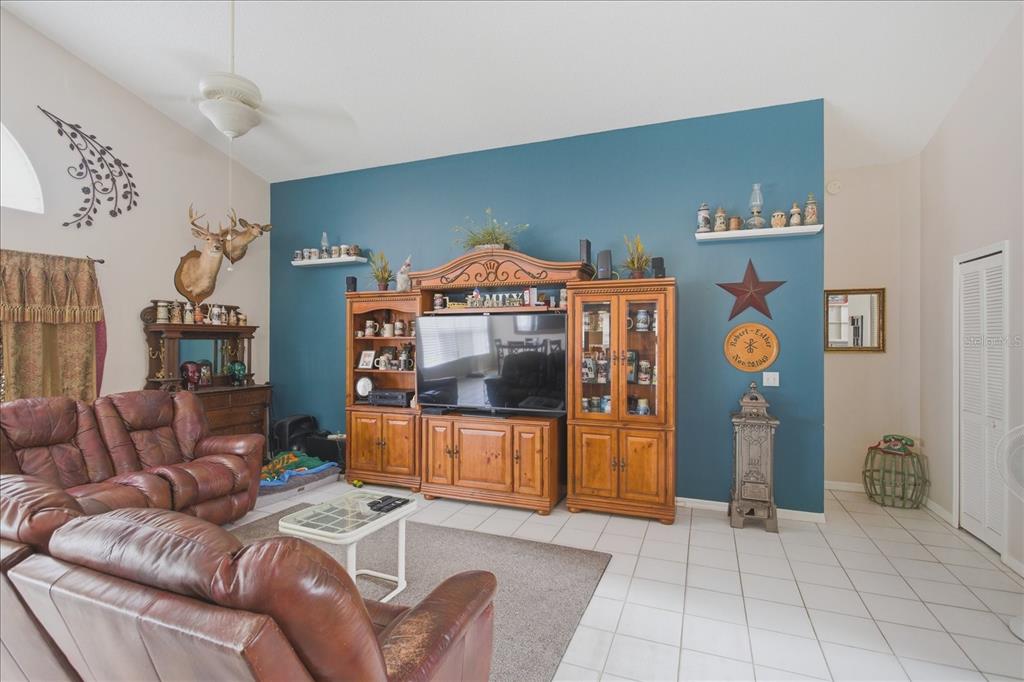 A living room features a blue accent wall, wooden entertainment center, and brown leather furniture — 108 N BRISTOL CIRCLE, SANFORD, FL