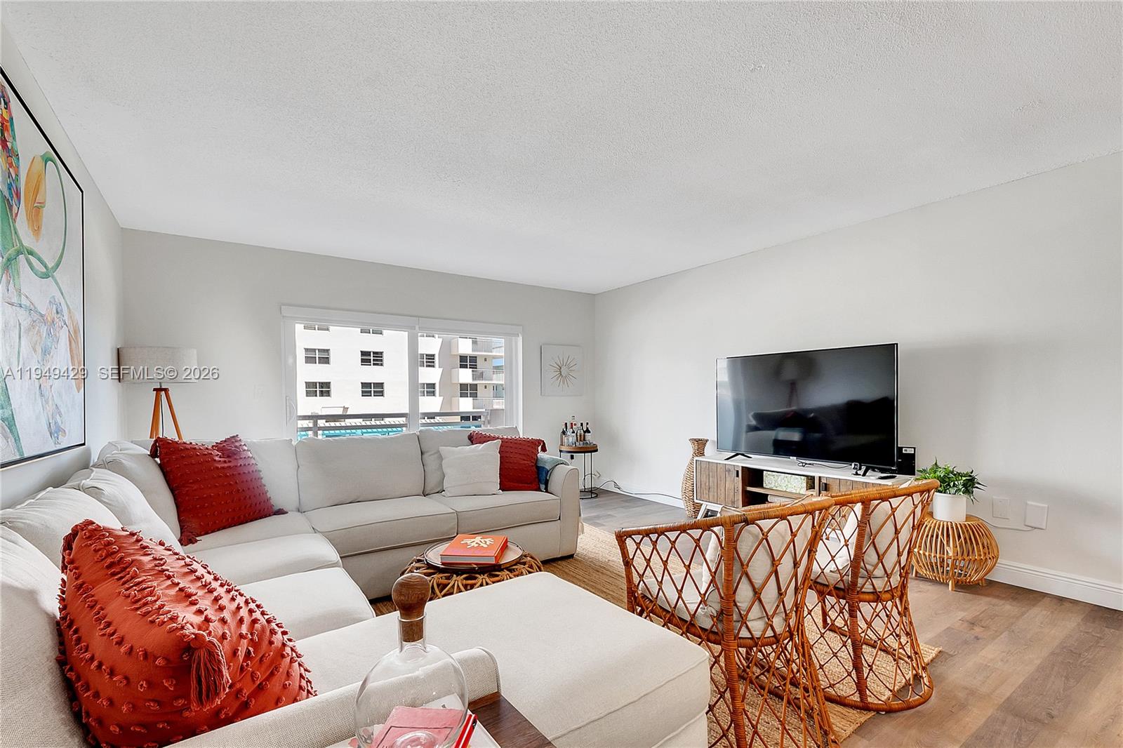 A living room features a white sectional sofa, two rattan chairs, and a television console — 1701 S Ocean Dr # 202, Hollywood FL 33019, HOLLYWOOD, FL