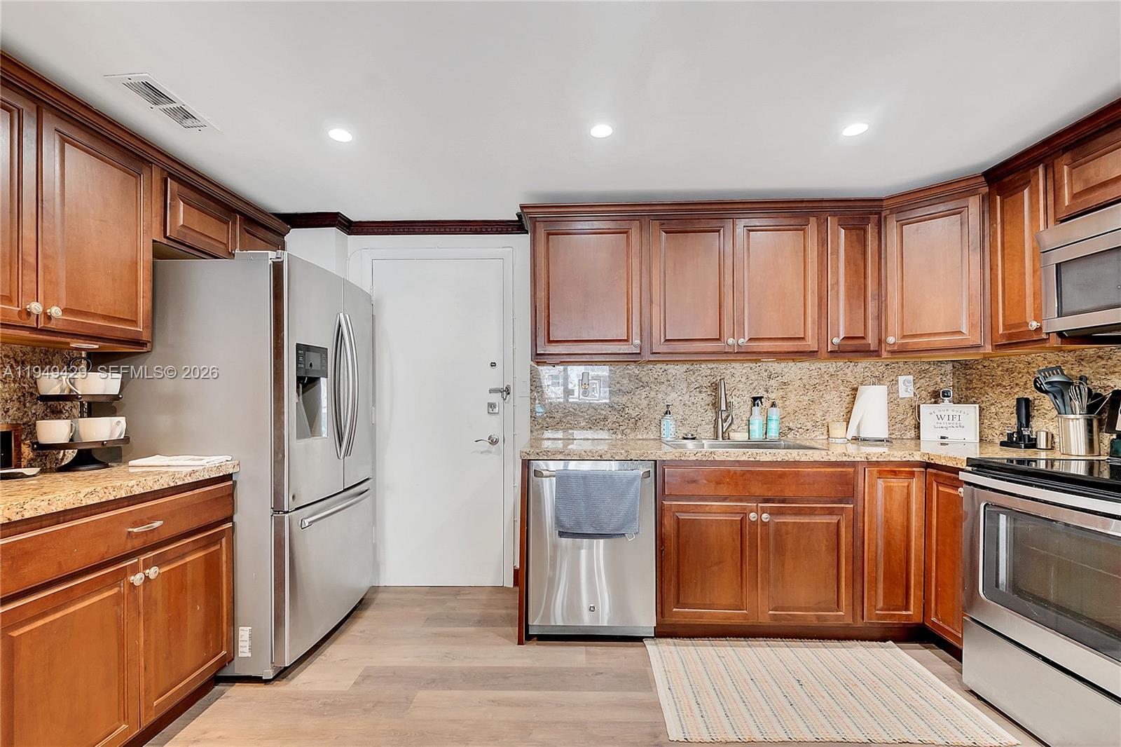 A kitchen features wood cabinets, granite countertops, and stainless steel appliances on wood-look flooring — 1701 S Ocean Dr # 202, Hollywood FL 33019, HOLLYWOOD, FL