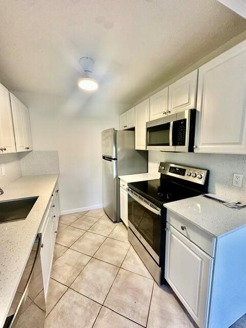 A kitchen features white cabinets, stainless steel appliances, and light-colored countertops — 1047 Exeter C, Boca Raton FL 33434, BOCA RATON, FL