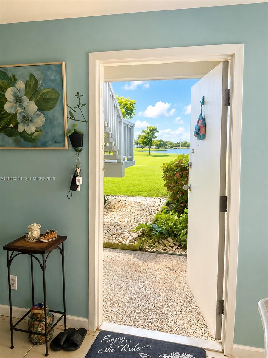 An open door reveals a view of a grassy lawn, a pond, and stairs — 116 Tuscany B # 116, Delray Beach FL 33446, DELRAY BEACH, FL