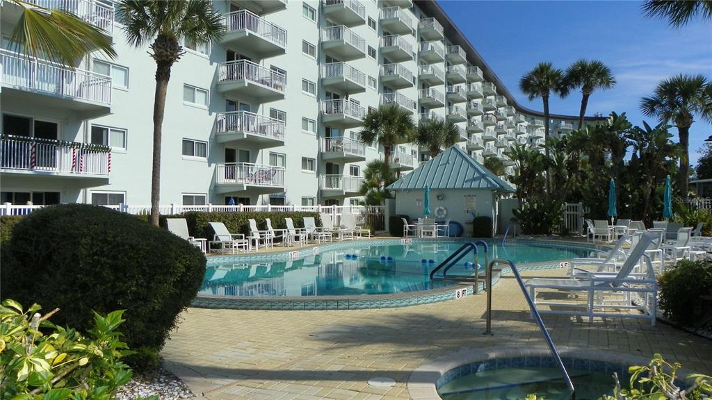 A swimming pool and hot tub sit on a patio beside a large apartment building — 100 SILVER BEACH AVENUE UNIT 214, DAYTONA BEACH, FL