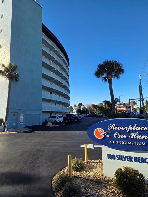 A multi-story condominium building stands next to a parking lot with a prominent entrance sign — 100 SILVER BEACH AVENUE UNIT 214, DAYTONA BEACH, FL