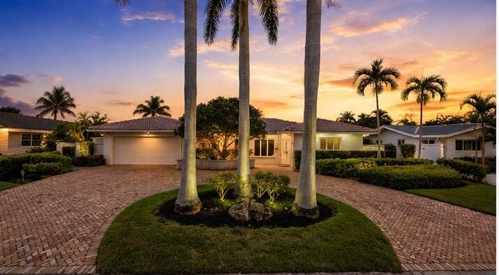A brick driveway leads to a single-story house surrounded by palm trees at sunset — 4220 NE 26th Avenue, Lighthouse Point FL 33064, LIGHTHOUSE POINT, FL