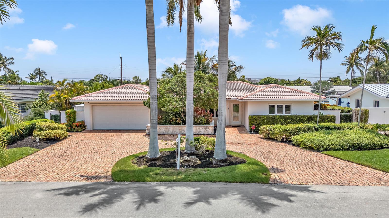 A single-story house with a brick driveway, three palm trees, and a two-car garage — 4220 NE 26th Avenue, Lighthouse Point FL 33064, LIGHTHOUSE POINT, FL