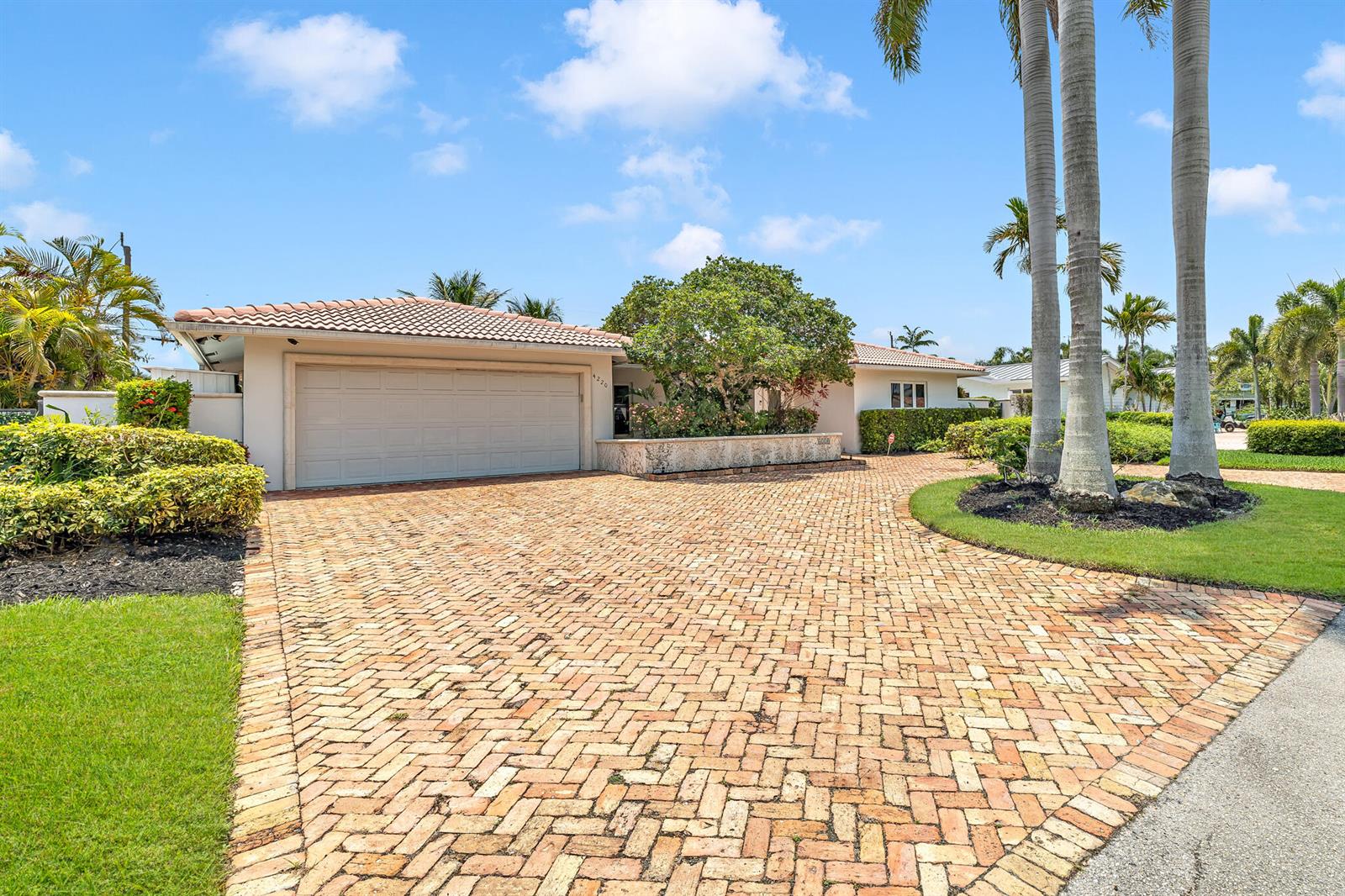 A single-story house with a brick driveway, a two-car garage, and tall palm trees — 4220 NE 26th Avenue, Lighthouse Point FL 33064, LIGHTHOUSE POINT, FL