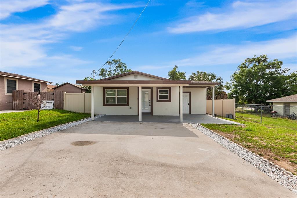 A single-story house with a concrete driveway, covered porch, and tan exterior walls — 1809 BARTLEY STREET, HAINES CITY, FL