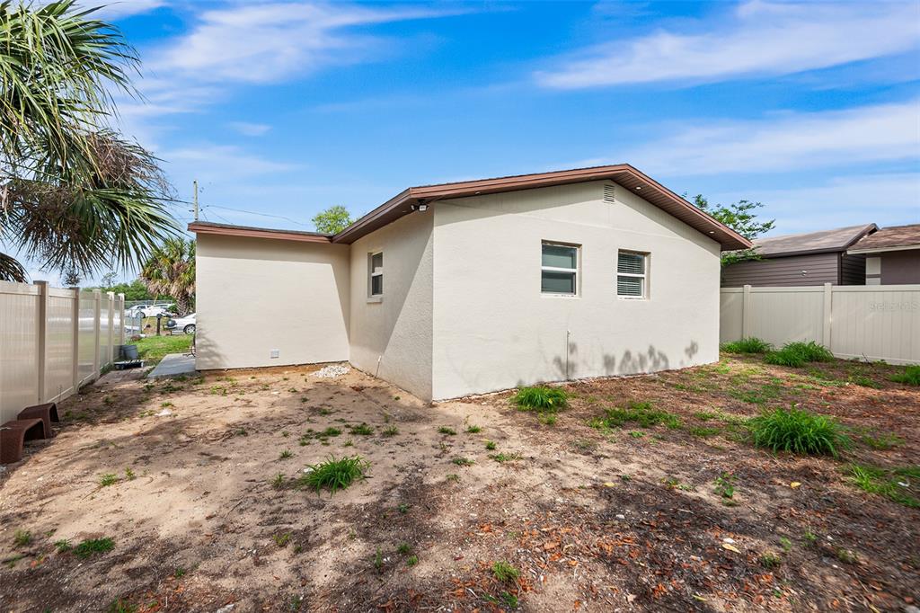 The exterior of a beige, single-story house with a brown roof and a fenced yard — 1809 BARTLEY STREET, HAINES CITY, FL