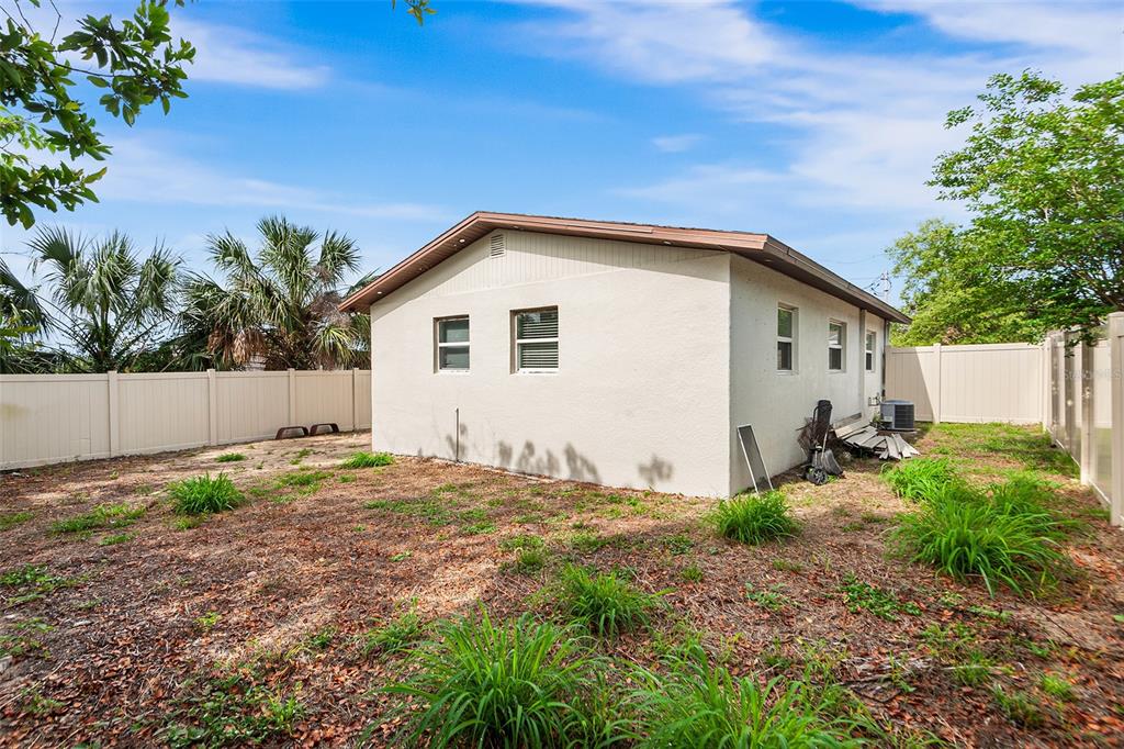The exterior of a single-story house with a white stucco finish and a fenced yard — 1809 BARTLEY STREET, HAINES CITY, FL