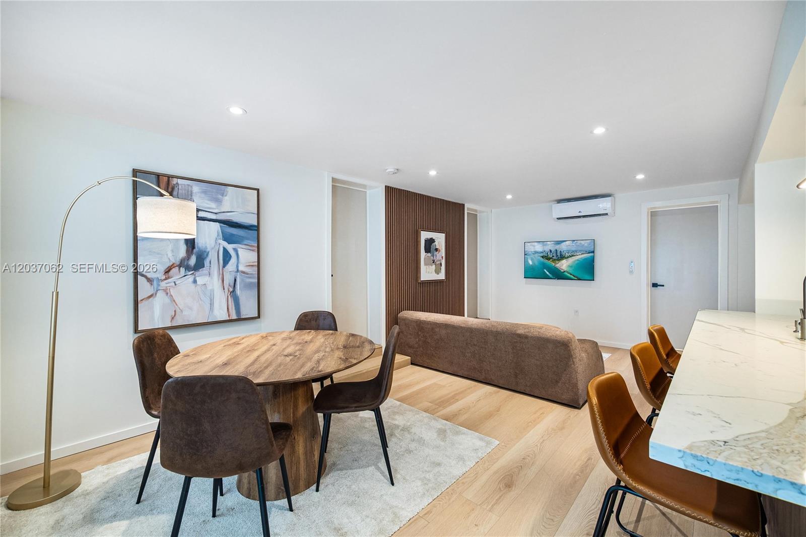 This open-concept living and dining area features wood-look flooring, a round table, and a sofa — 3681 SW 3rd Ave # 3681, Miami FL 33145, MIAMI, FL