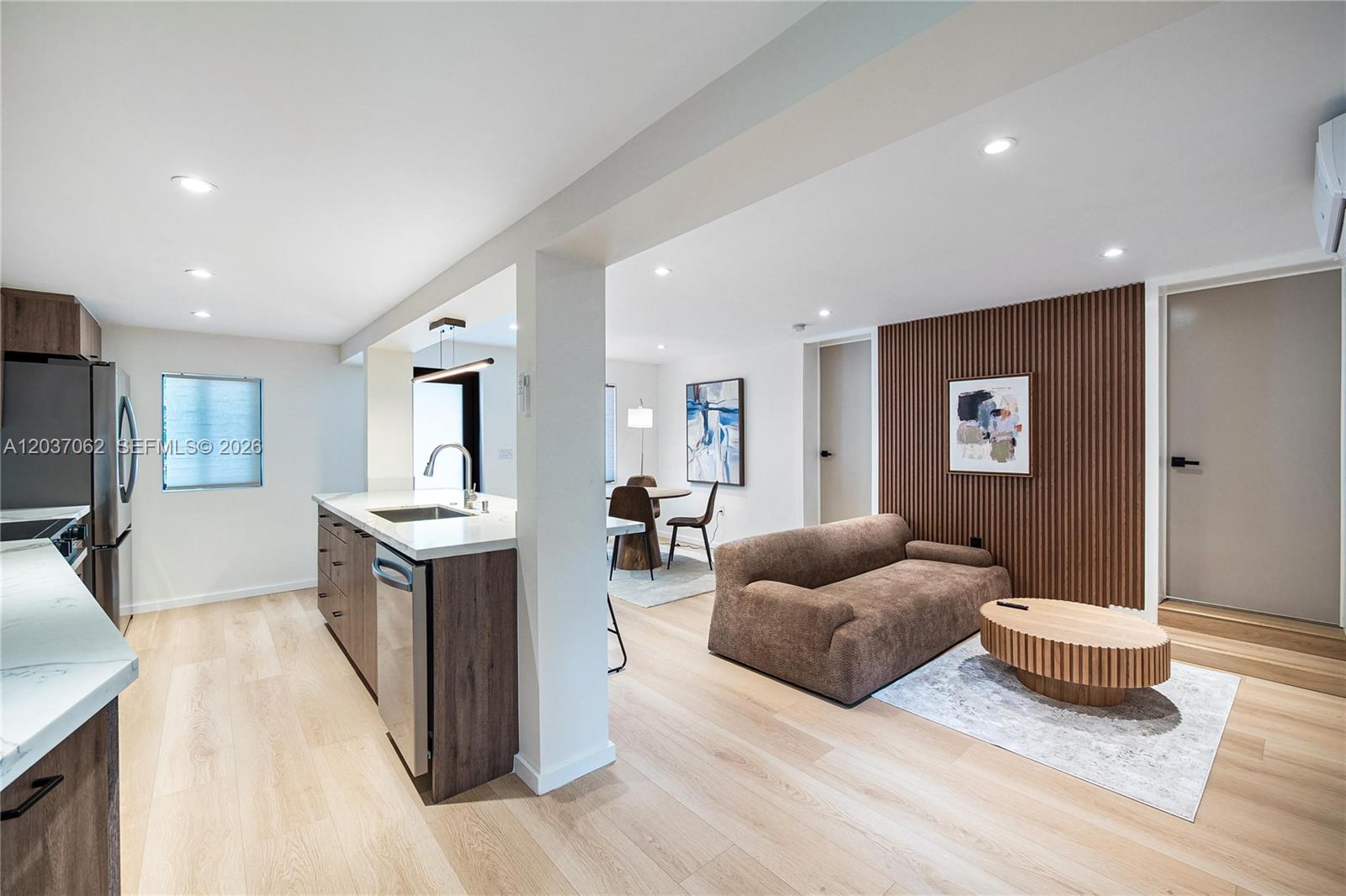 A modern open-concept kitchen and living area features wood-slat wall paneling and light flooring — 3681 SW 3rd Ave # 3681, Miami FL 33145, MIAMI, FL