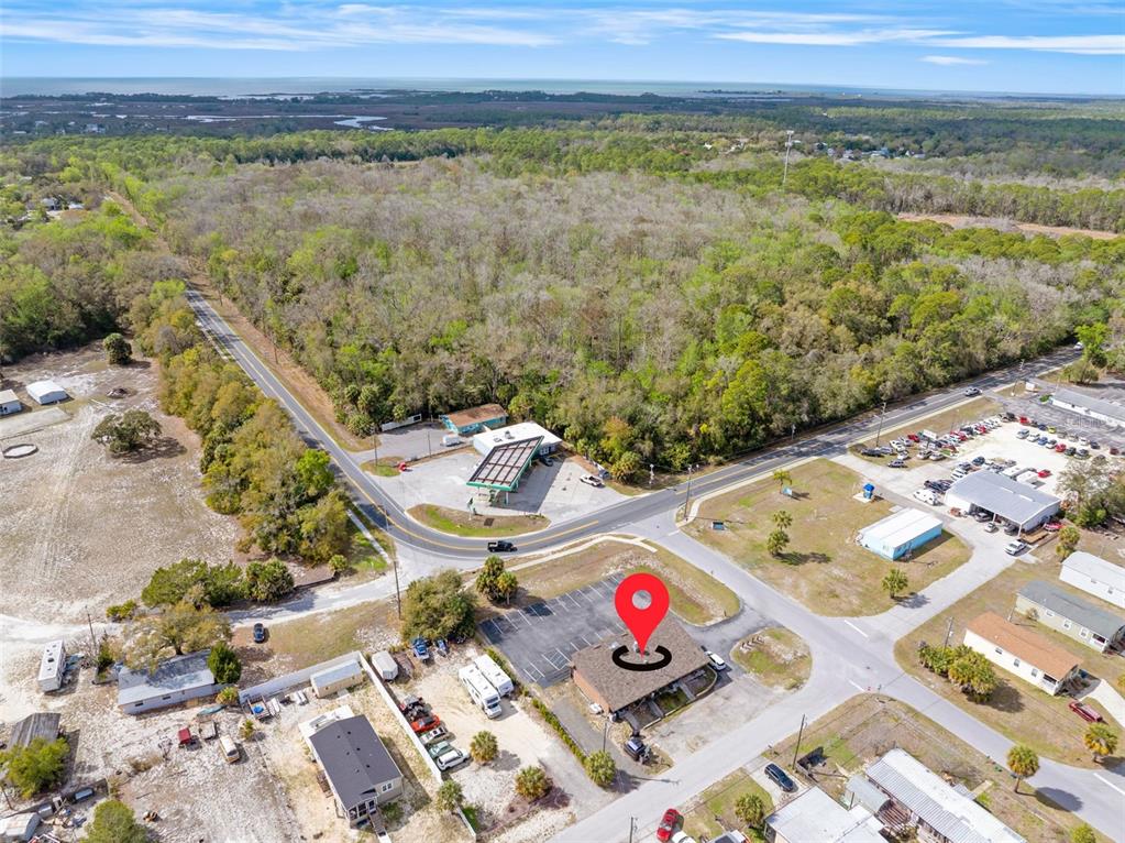 An aerial view shows a commercial building with a parking lot near a road intersection — 7390 SHOAL LINE BOULEVARD, WEEKI WACHEE, FL